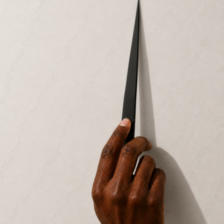 Matte black pointed fragrance testing strip on a cream stone surface with soft natural lighting and minimalist styling.