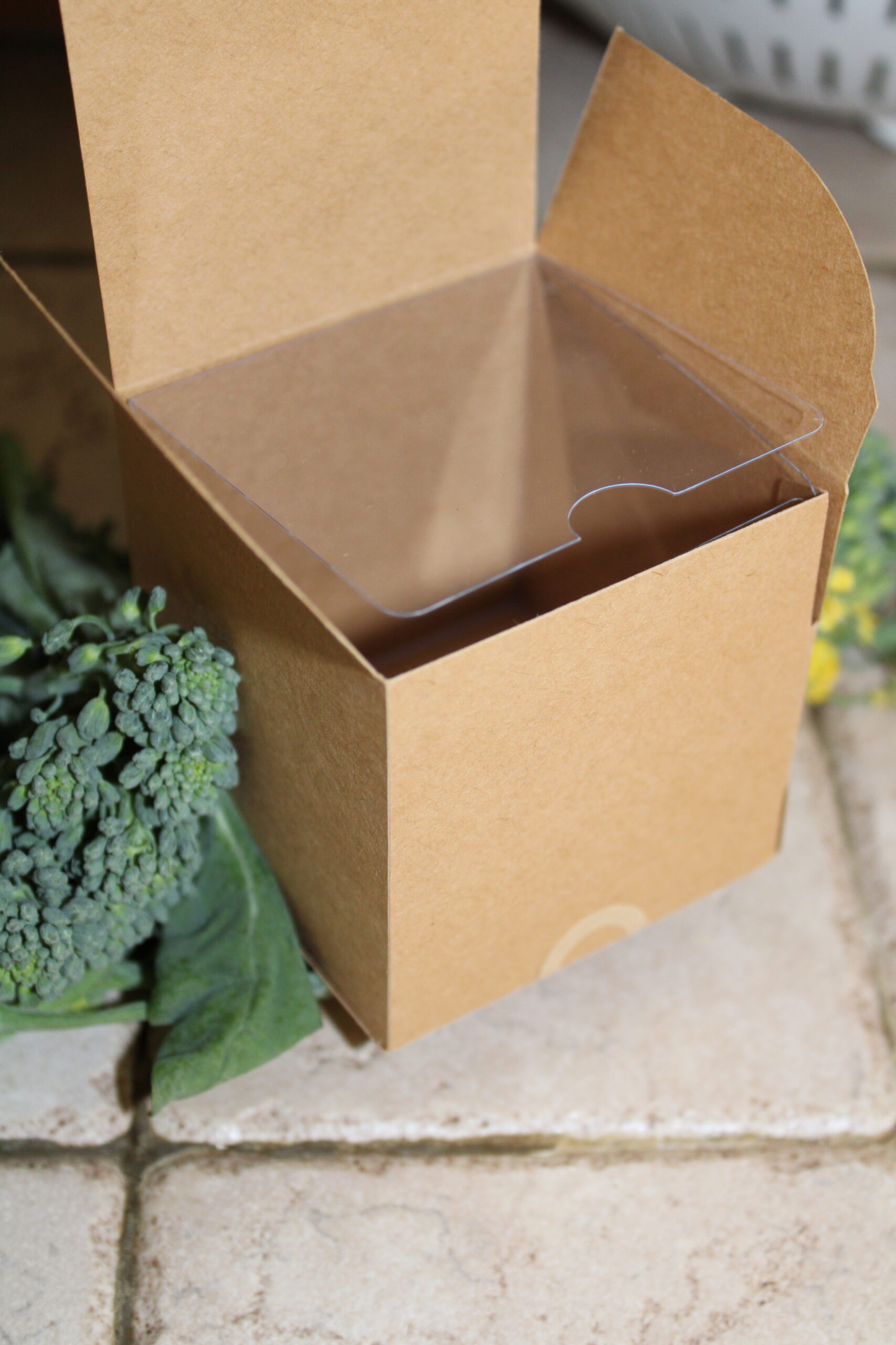 Kraft Cream Jar Square Box with a clear plastic insert sitting open on bed of broccoli