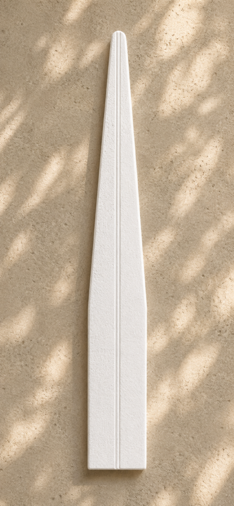 Tall matte white scent strip with elongated tapered silhouette and soft porous texture resting on a creamy sandstone surface with natural leaf-shadow lighting.