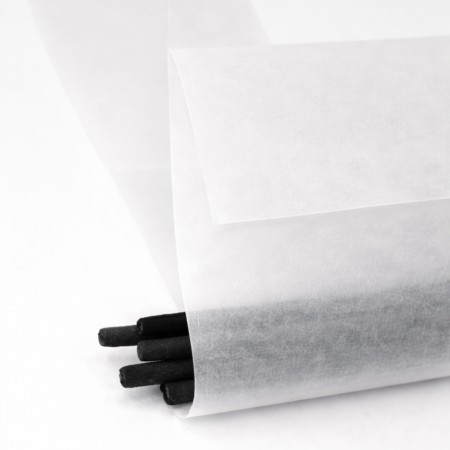 Bundle of black incense sticks partially wrapped in translucent vellum paper, with the frosted material softly revealing the sticks inside against a clean white background.
